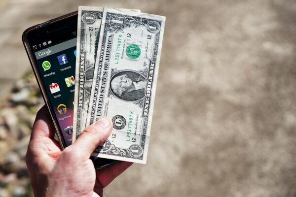 Persom Holding Black Android Smartphone and 2 1 U.s. Dollar