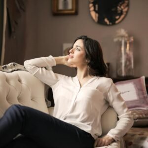 A serene woman enjoys a moment of reflection on a luxurious vintage sofa in a well-designed interior.